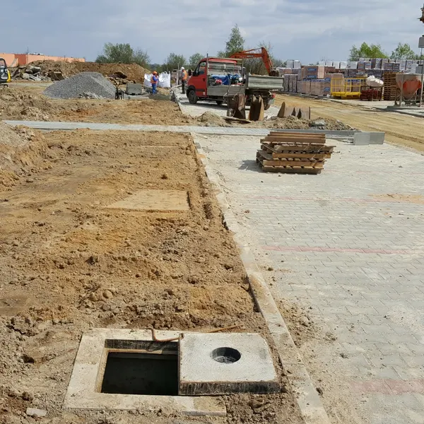 Studnia kablowa CityNet z odkryta pokrywa na terenie budowy osiedla w Rzeszowie — ukladanie kanalizacji teletechnicznej dla sieci swiatlowodowej rownolegle z robotami drogowymi.