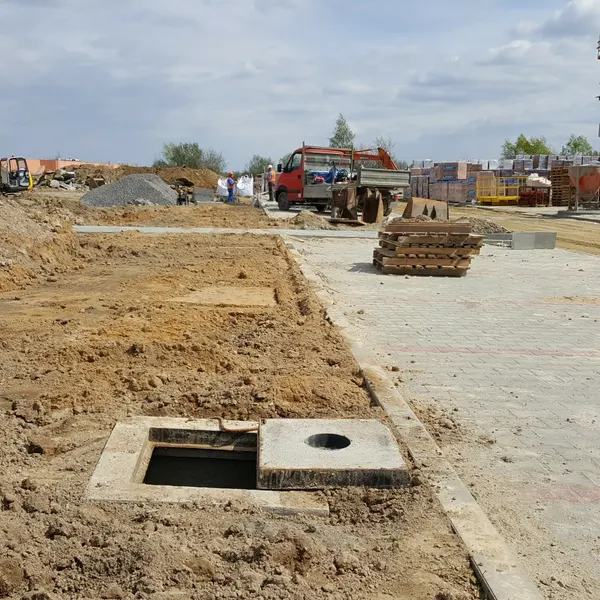 Otwarta studnia kablowa CityNet przy swiezo ukladanej kostce na osiedlu w budowie w Rzeszowie — kanalizacja teletechniczna pod przylacza swiatlowodowe.